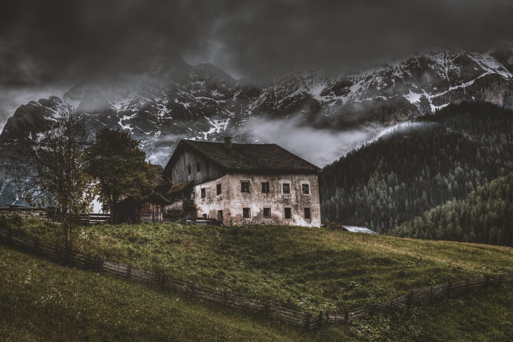 opuszczony stary dom na zboczu góry, w tle ośnieżone szczyty